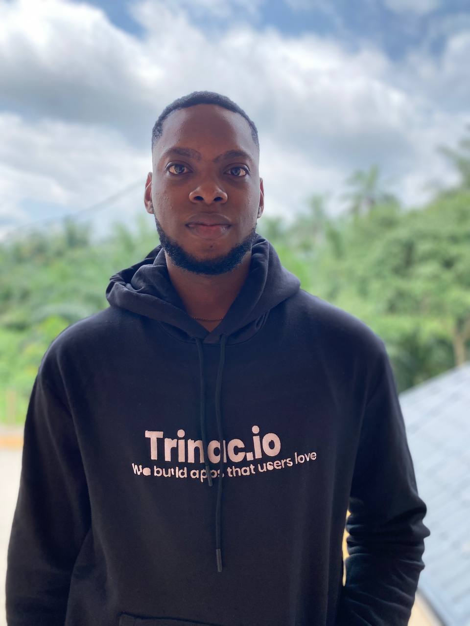 Chuks Ben Okafor, outdoors against trees and an overcast sky